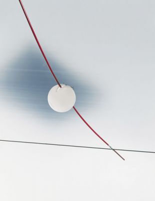 Nahaufnahme der Ingo Maurer YAYAHO Leuchte: Weiße Kugel mit rotem Kabel, modernes Design Lichtsystem.